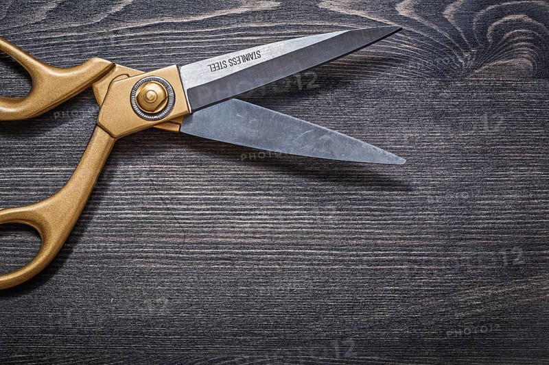 Pair of golden scissors on vintage wooden board top view