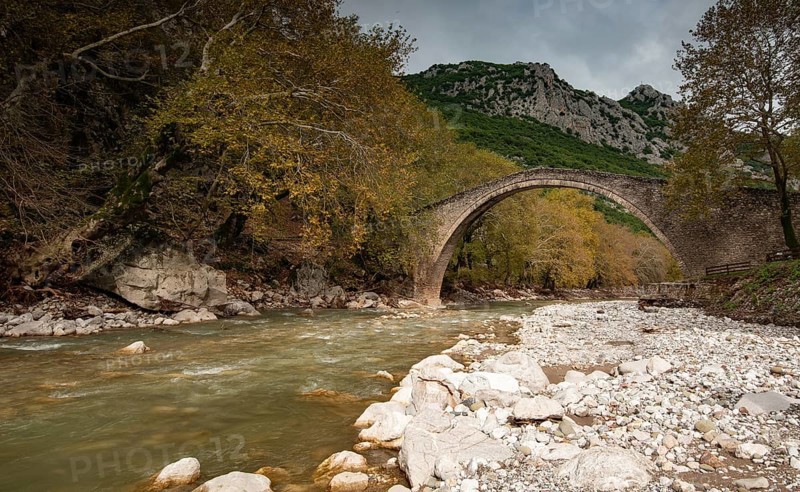 Ancient, stoned, arched bridge St. Vissarion on the Portaikos river in autumn. Trikalla pyli village Thessaly Greece