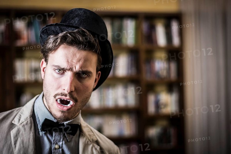 Close up Young Handsome White Vampire with Black Top Hat Inside the Mini Library