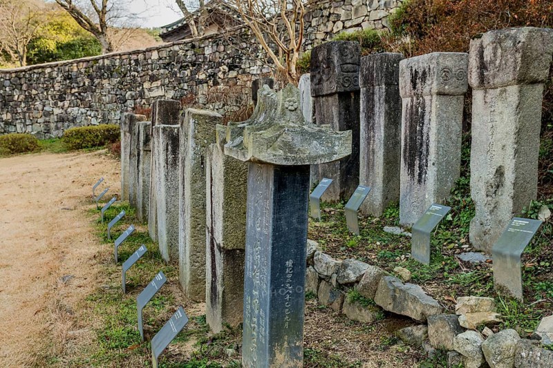 Gochang, South Korea, December 4, 2020: Stone stelae honoring Korean monks with fortress wall in background, Asia