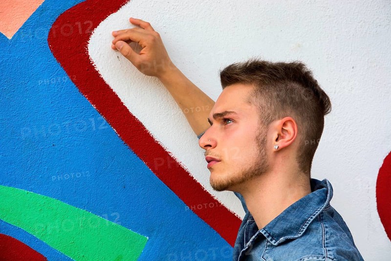 Attractive young blond man against colorful graffiti wall, wearing denim shirt