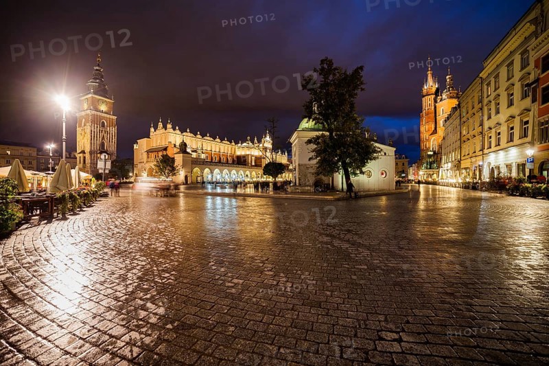Poland, Krakow, Main Square in Old Town after the rain, city skyline at night with Town Hall Tower, Cloth Hall and St Mary Church, Europe
