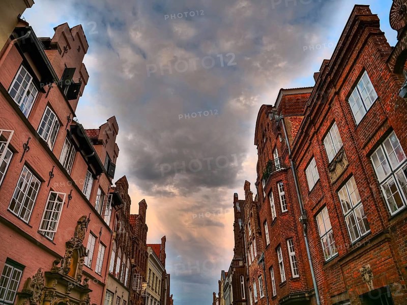 Historic red brick buildings under a dramatic cloudy sky, gothmund, travemünde, lübeck, germany