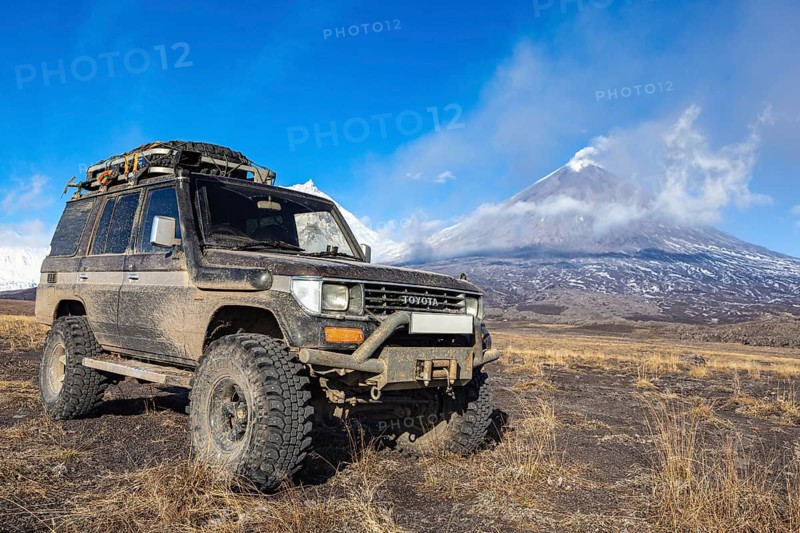 Lifted sport utility vehicle Toyota Land Cruiser Prado on background eruption active Klyuchevskoy Volcano. Car modified transmission for travel, extreme off-road trip. Kamchatka, Russia, Oct 1, 2016, Europe