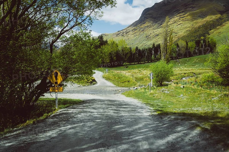 Gravel road in a rural setting with trees and signposts, Cattle Flat, Wanaka, New Zealand, Oceania