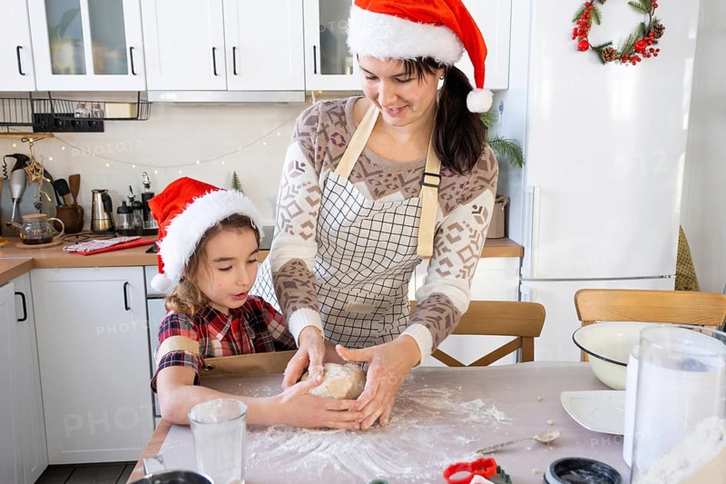 Mom and daughter in the white kitchen are preparing cookies for Christmas and new year. Family day, preparation for the holiday, learn to cook delicious pastries, cut shapes out of dough with molds