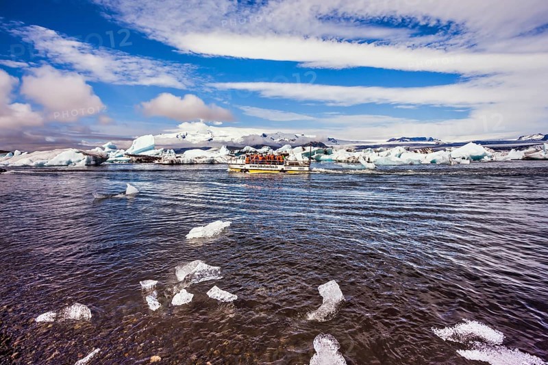 The trash-ice on Jokulsarlon, Iceland. Striped clouds beautifully reflected in the smooth water of lagoon. The concept of northern extreme tourism
