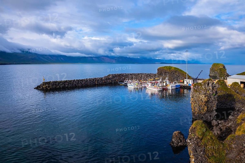 White fishing boat in the harbor pier fishing village Arnastapi. Sunset on the sea fjord in Iceland