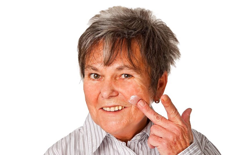 Senior woman with cream pot cropped on white background
