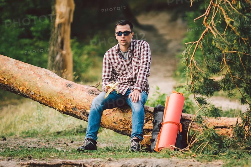 Eating banana Outdoors Hiking Trail. theme hiking and nature travel. Tourist take a rest and eating babanas. picnic in the forest. tourist eat snack food. Vitamin charge