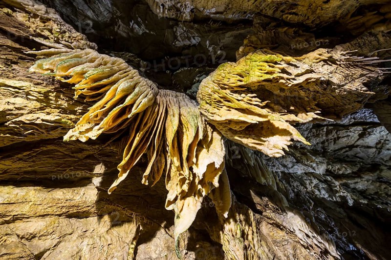 Inside of a beautiful colourful cave. Flowstones, stalactites and stalagmites lighted in different vivid colours