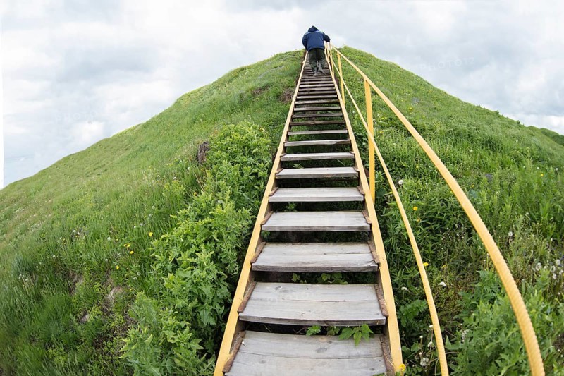A man climbs up a hill on a ladder