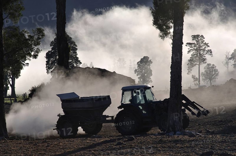 Tractor spreading lime with a fertiliser spreader, West Coast, New Zealand, Oceania