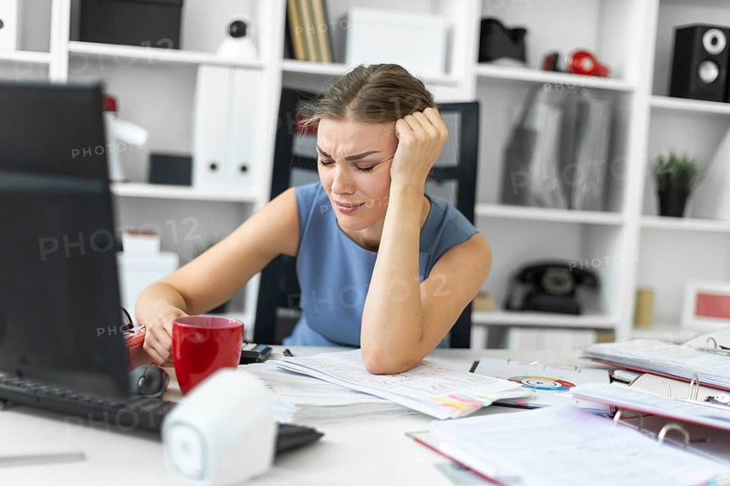 Beautiful young girl in a blue dress is working in the office. photo with depth of field