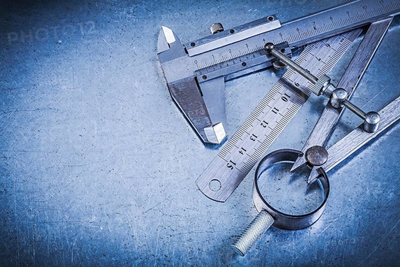 Metal ruler slide caliper construction pair of compasses on metallic background