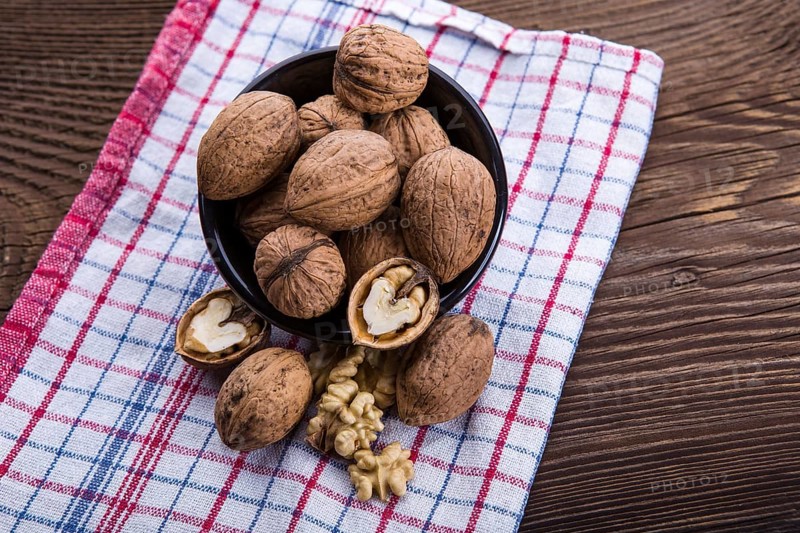 Walnut kernels and whole walnuts on old wooden table and dish towel