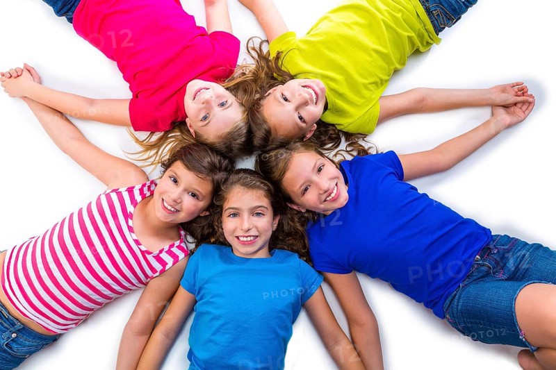 Happy kid friend girls group smiling aerial view lying on circle over white background holding hands