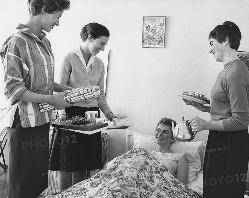 Birthday in the 1960s. A young woman lies in bed and is surprised by her girl friends singing happy birthday to you. They have all three wrapped presents ready. A coffee tray and coffee from a silver pot and cake are also included. Sweden 1961