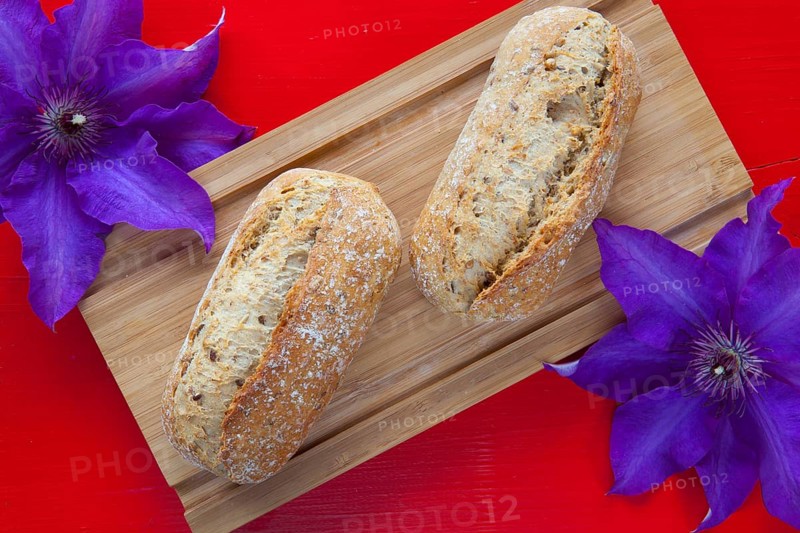 Fragrant breakfast - Two wheat bread and clematis flower on wooden desk