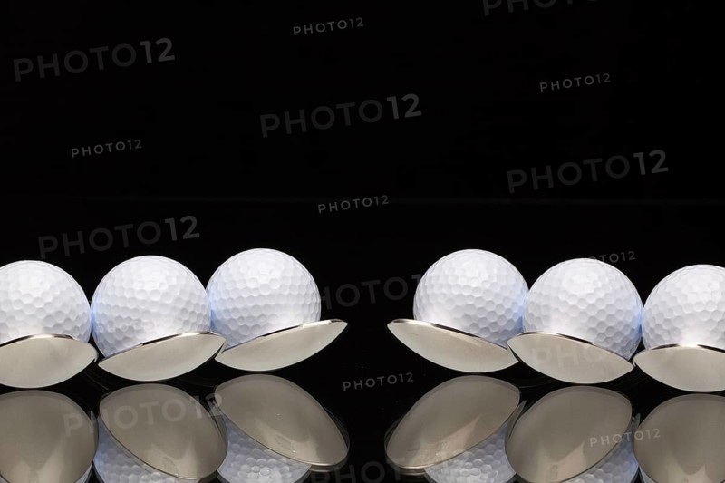 Six spoons and golf balls on a black glass desk