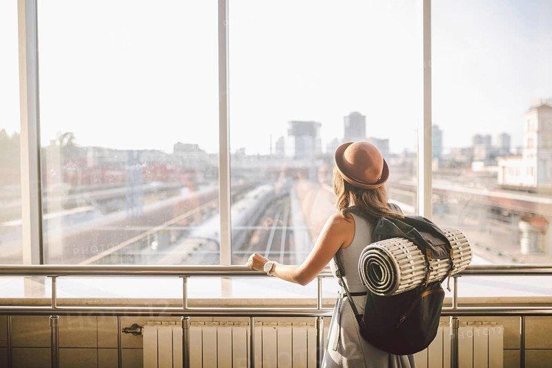 Traveler Rear view woman standing at the window in hall Train Station departure with backpack, Selective focus, Travel concept. transportation concept. Theme travel public transport