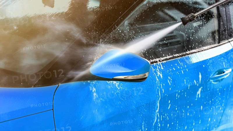 Side mirror of blue car washed in self serve carwash, jet water sprays from high pressure nozzle, Liptovsky Mikulas, Slovakia, Europe