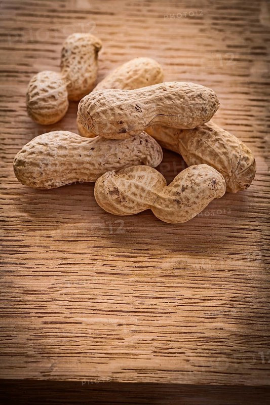 Small stack of peanuts on vintage wooden board food and drink concept