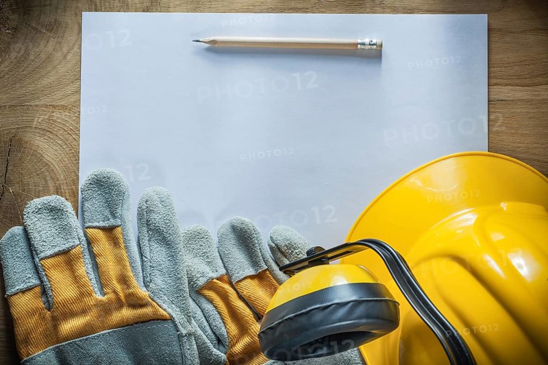 Pencil paper protective gloves hard hat earmuffs on wooden board