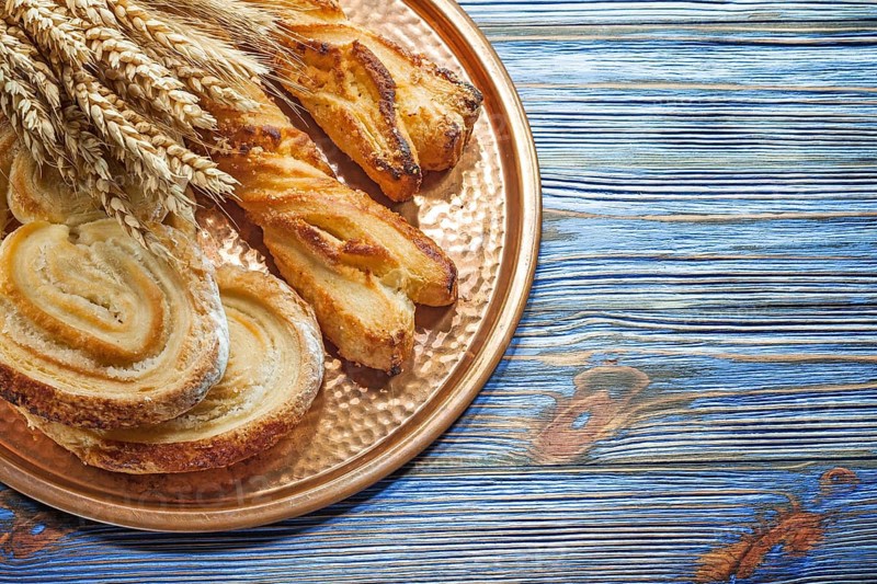 Wheat ears crusty rolls brass tray on vintage wooden board