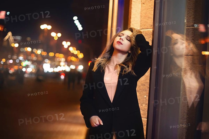 Portrait of Beautiful young woman in black on a background of a night city. night life