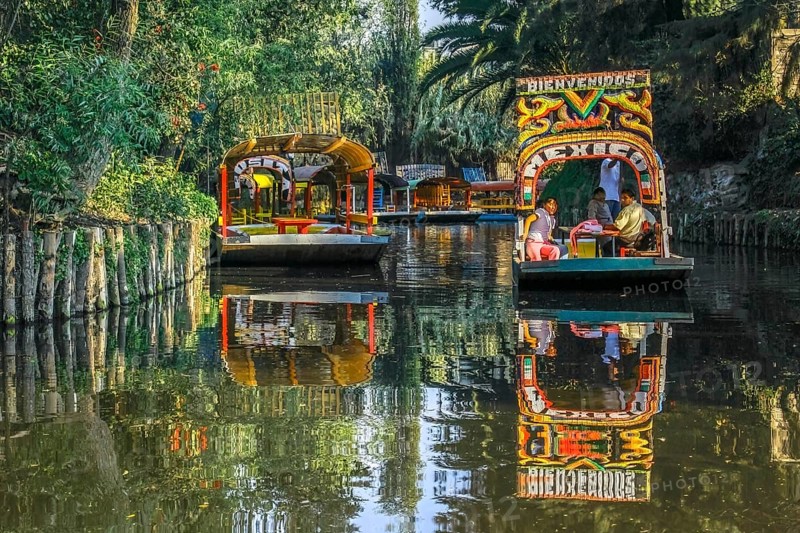 Mexico City, Mexico. Jan 11, 2024. A couple of Trajinera a gondola style boats, or colourful rafts gliding along the Xochimilco canals, with tourists enjoying the ride