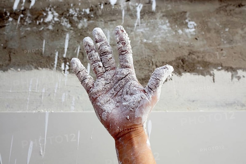 Astist plastering man hand with white dried cracked plaster texture in fingers
