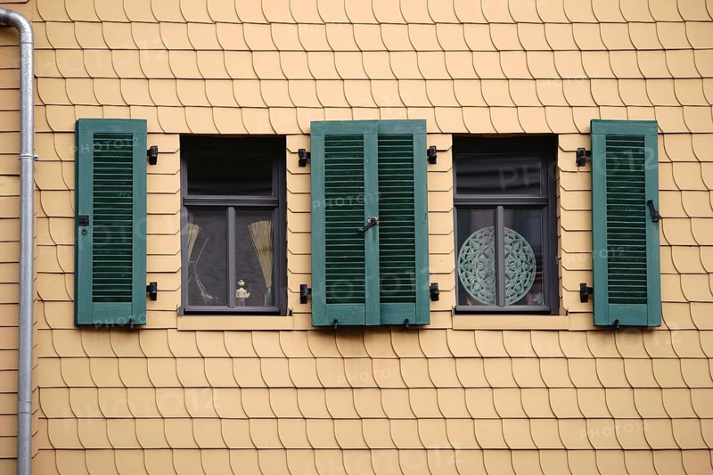 Open shutters on a striking façade of yellow shingles
