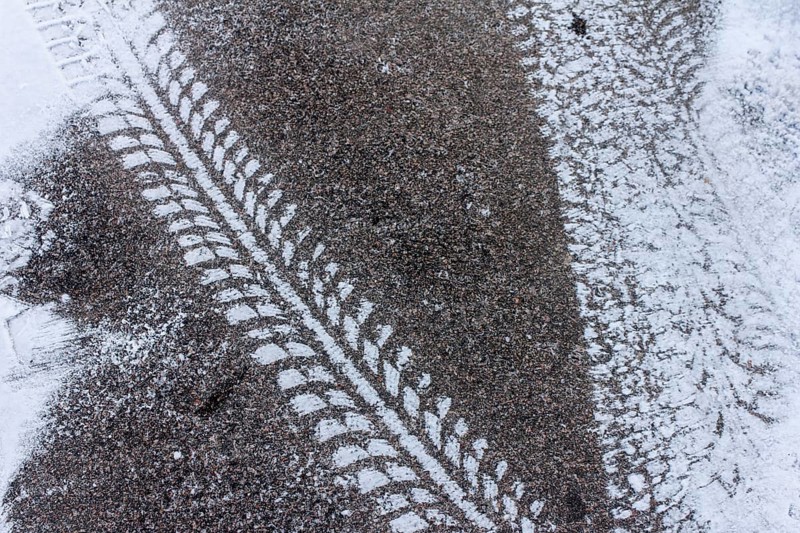 Tyre tracks on snow-covered asphalt, high-contrast texture in winter