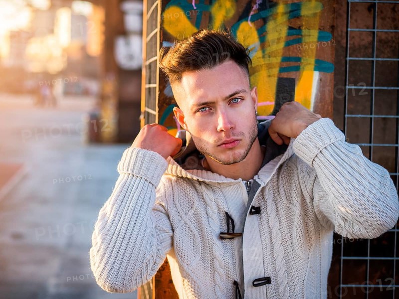One handsome young man in urban setting in moden city, standing, wearing black coat and scarf in winter day