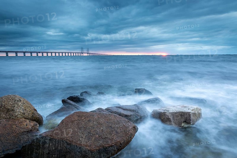A stormy sea with rocks in the foreground and a bridge in the background, Öresund Bridge, Øresundsbroen, the world's longest cable-stayed bridge, connecting Copenhagen with Malmö