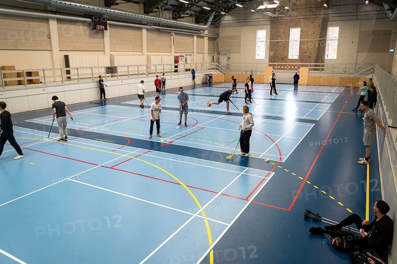 February 21, 2019. Denmark. Copenhagen. Team game with stick and ball Floorball or hockey in hall. Inside training in the gym of the school college. Group of teen caucasian students playing a game