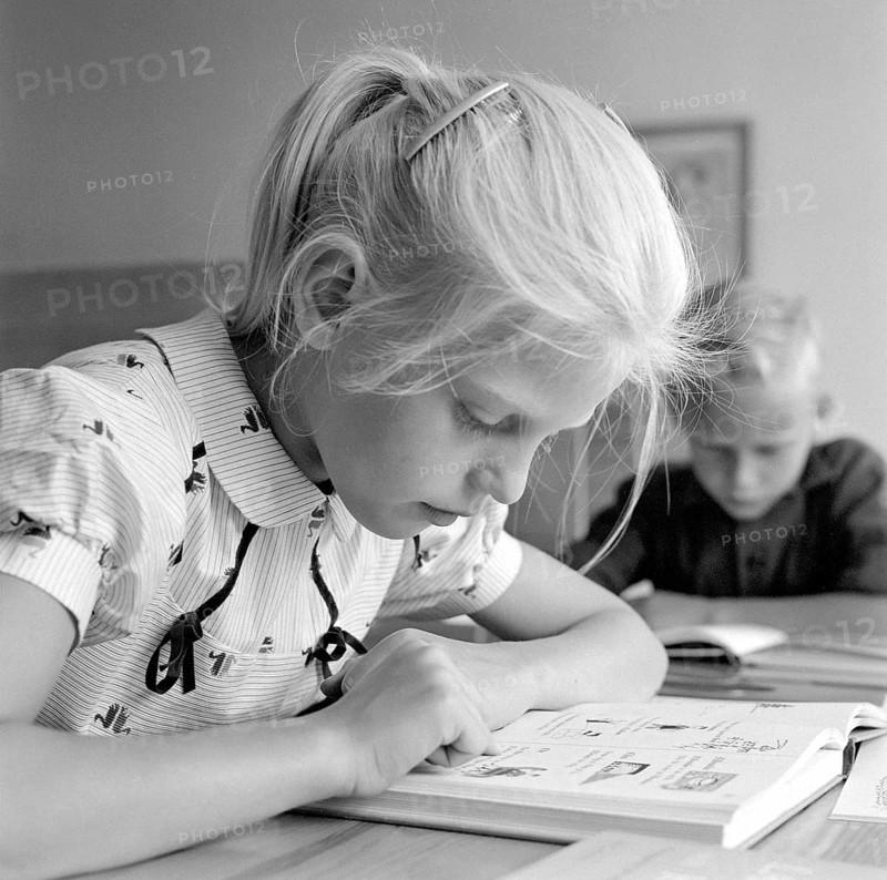 School in the 1950s. A girl is seen sitting at her desk in the classroom reading from the schoolbook in front of her. Sweden 1957 Conard ref 3538