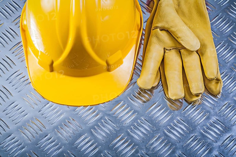 Protective leather gloves hard hat on corrugated metal background construction concept