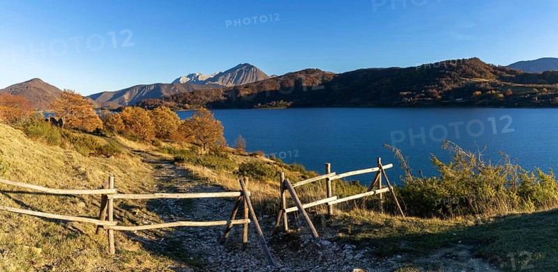 A wooden fence and hiking trail on the banks of Campotosto Lake in the mountains of Abruzzo in Italy