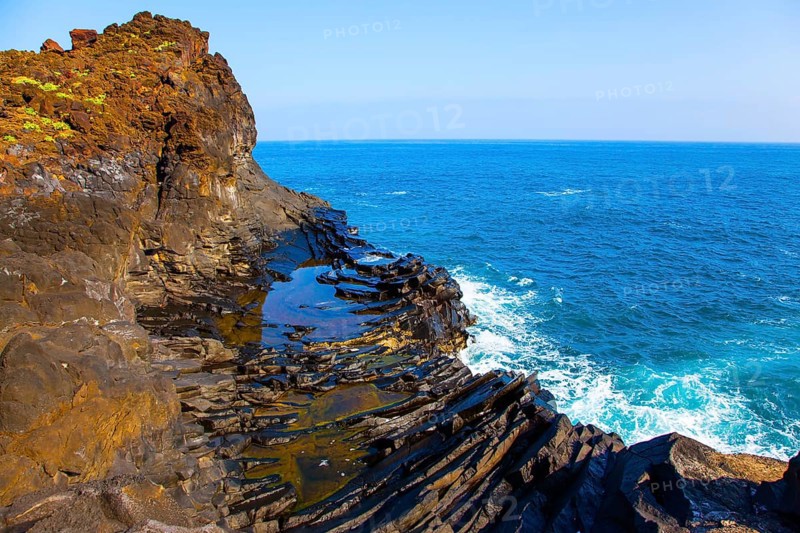 Small bay with azure water. Volcanic island of Madeira. Grottoes and rocks of the Atlantic coast. The concept of ecological and exotic tourism