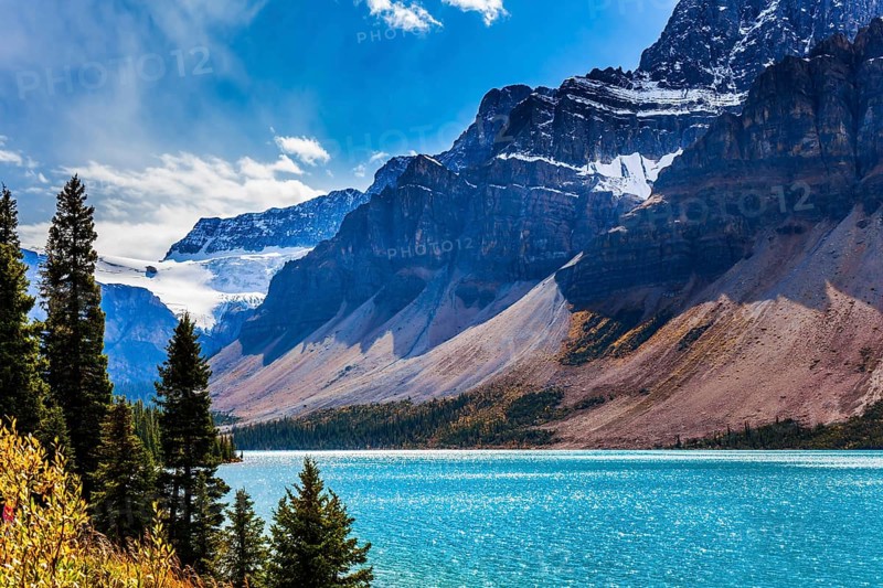 The Rockies of Canada. The picturesque huge and deep Lake Bow is surrounded by cliffs and glaciers. The wind drives lush cumulus clouds. The concept of active and photo tourism