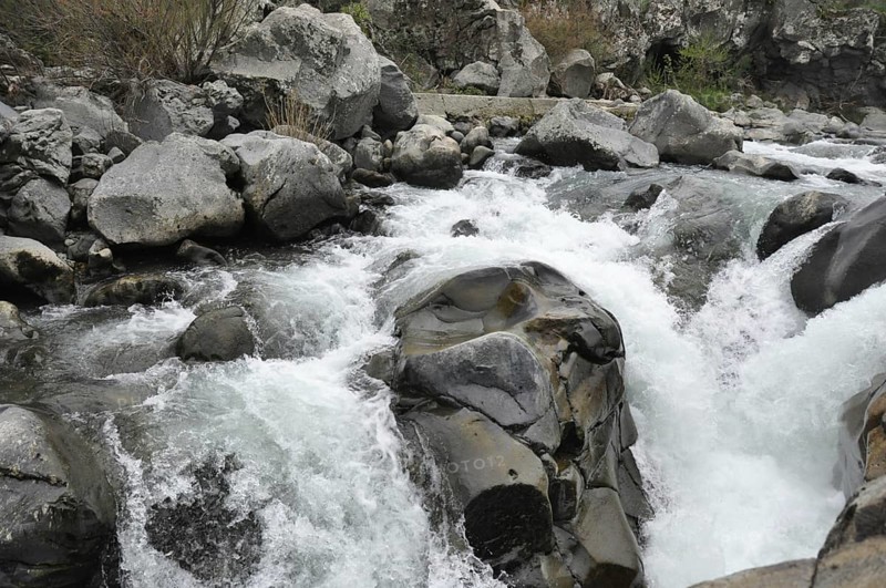 Whitewater rapids swirling around large rocks in a river, The Alcantara Park is located on the northern slope of Mount Etna, between the provinces of Messina and Catania in Sicily. The Alcantara gorges were created by the waters of the river flowing through lava flows from Mount Etna. The park is home to several plant species, including plane trees, oaks, willows and oleanders, and a variety of animals, including migratory birds, mammals and fish