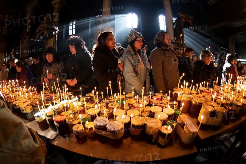 Blagoevgrad, Bulgaria - February 10, 2019: Worshippers light candles on jars with honey during a religious ritual marking the day of Saint Haralampi - the Orthodox patron saint of beekeepers - in the church of the Presentation of the Blessed Virgin