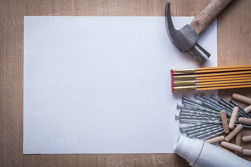 Wooden meter rolled construction plans blank paper metal nails claw hammer heap of fluted dowels on wood board copy space maintenance concept