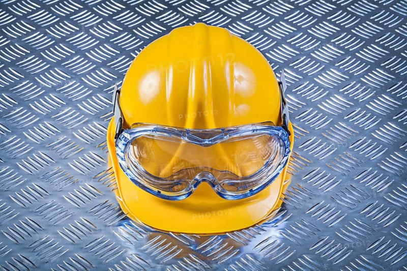 Safety glasses hard hat on grooved metal plate construction concept