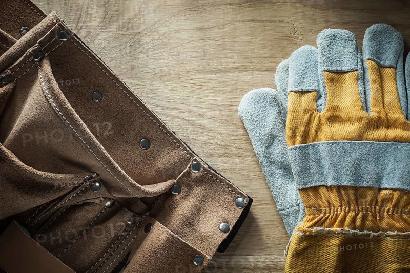 Leather building belt pair of protective gloves on wooden board