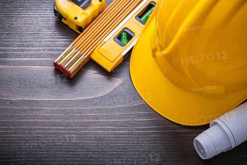 Tape-line blueprints construction level hard hat and wooden meter on vintage wood board maintenance concept