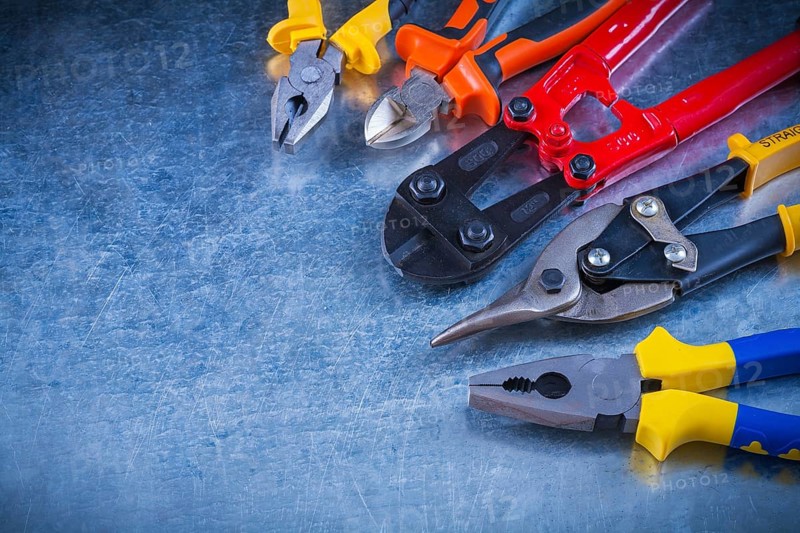 Set of bolt cutter tin snips cutting pliers gripping tongs on scratched vintage metallic surface construction concept