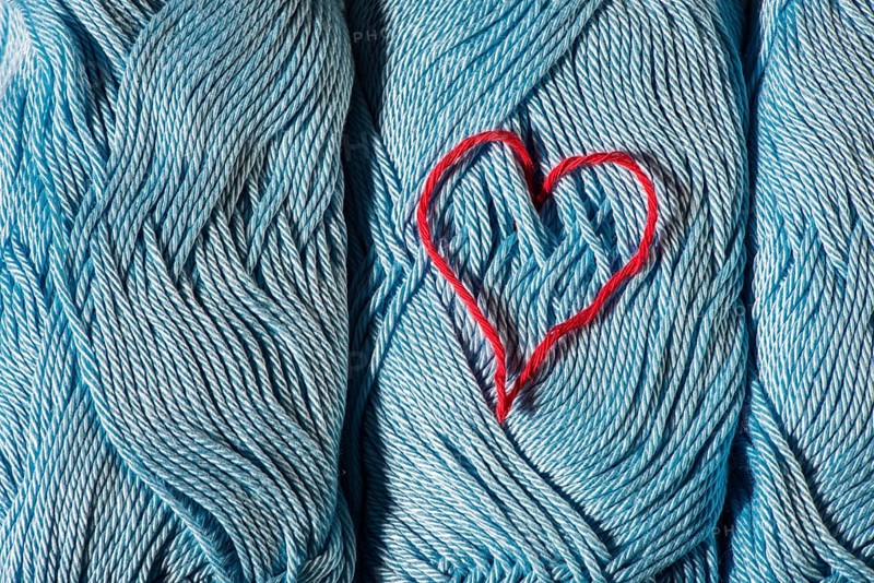 Knitted red heart on blue balls of yarn